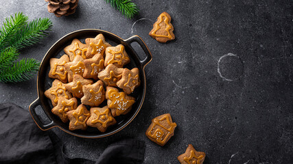  Festive Christmas cookies decorated with golden icing in a black plate. Dark grey background, top view, copy space for text