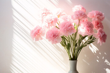 Obraz premium Pink Carnations Bouquet on White Wall Background with Sunlight Shadows for Home Decor