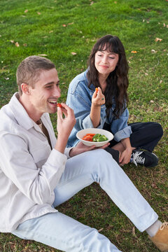 Couple eats vegetables in park
