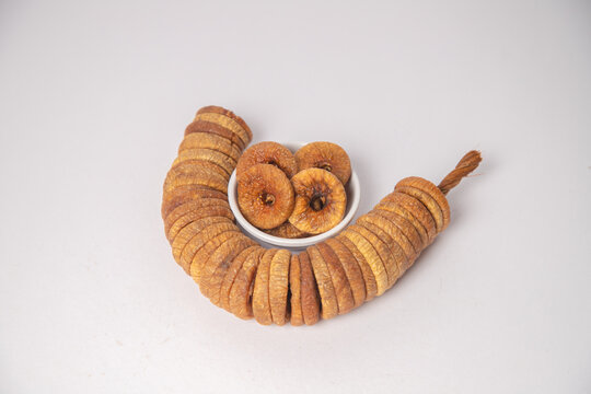 Figs or dried figs on white bowl with white background, Figs or dried figs arranged in round shaped on the white background in a wooden bowl. The fig is the edible fruit of Ficus Carica