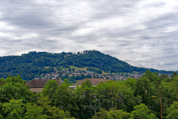 Fototapeta na wymiar Scenic view of mountain panorama and woodland with local mountain Gurten seen from the old town of City of Bern on a cloudy summer day. Photo taken July 1st, 2023, Bern, Switzerland.
