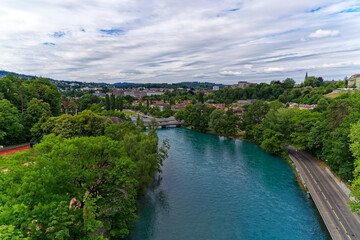 Fototapeta na wymiar Scenic aerial view of Aare River with trees alongside urban road at Swiss City of Bern a cloudy summer day. Photo taken July 1st, 2023, Bern, Switzerland.