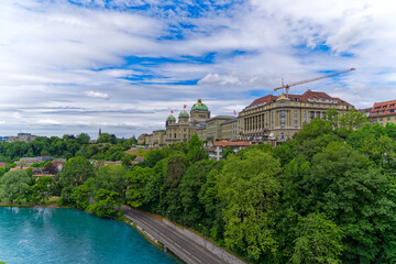 Fototapeta na wymiar Scenic view of Swiss Federal Palace with Aare River in the foreground on a cloudy summer day at Bern, Capital of Switzerland. Photo taken July 1st, 2023, Bern, Switzerland.