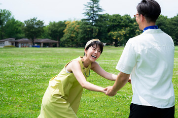 Beautiful Asian couple laughing and frolicking happily hand in hand in a lush green park. 