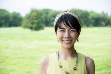 Portrait of a beautiful Asian woman happily smiling in a lush green park.