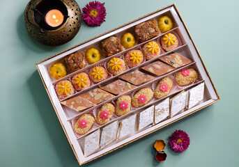 Indian assorted Diwali sweets or mithai box with diya and flowers. Festive gift idea. Kaju katli, dry fruits peda, barfi, cashew nut barfi, marzipan, khoya cakes. christmas box. copy space.