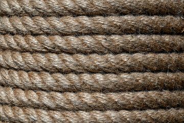 Natural jute hemp rope rolled into a coil, closeup. Brown spool of linen rope texture on the background