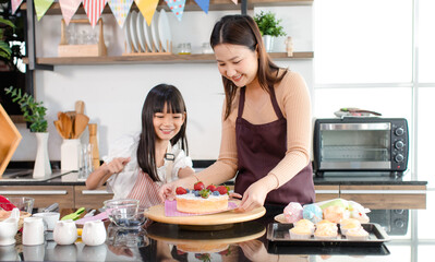 Asian beautiful female baker pastry chef mother wears apron standing smiling helping teaching...