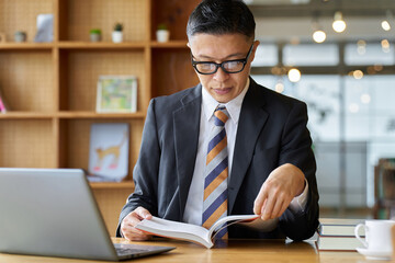 勉強のためカフェで読書をするアジア人ビジネスマン