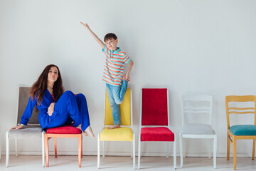 Mom with little boy sitting on colored chairs having fun