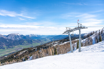 Ski lift in alpine ski resort. Late winter snow in the mountains and green grass in the valley....