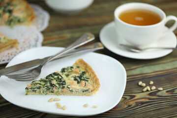 Delicious Quiche pie with salmon fish and pine nuts filling. Breakfast with quiche and cup of tea
