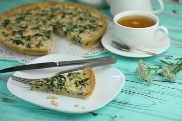 Fototapeta na wymiar Delicious Quiche pie with salmon fish and pine nuts filling. Breakfast with quiche and cup of tea
