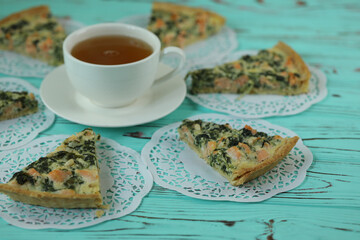 Delicious Quiche pie with salmon fish and pine nuts filling. Breakfast with quiche and cup of tea