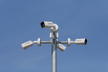 Pole mounted security cameras against blue sky