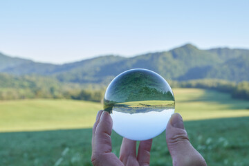 Beautiful landscape of the Carpathian Mountains in Poland, a sunny day with a meadow and green, flowered mountains, seen through a crystal ball that goes around the landscape, in Europe