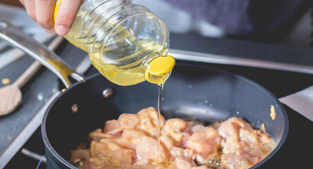 Cook pouring oil into a hot saucepan
