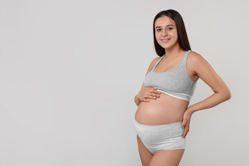 Beautiful pregnant woman in comfortable maternity underwear on grey background, space for text