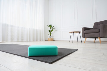 Exercise mat and yoga block indoors, low angle view