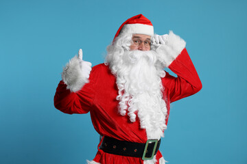 Merry Christmas. Santa Claus showing thumbs up on light blue background
