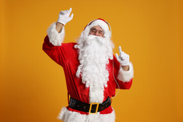 Merry Christmas. Santa Claus with headphones listening to music on orange background