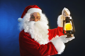 Merry Christmas. Santa Claus with vintage lantern on dark blue background