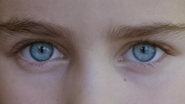 Blue Eye of Child Looking at Camera Close Up. Macro Shot Opening and Closing Blue Eyes Little Girl. Close Up Motion of Children Eyes. Human eye iris opening pupil. 