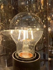 Luminous Reflections.A glowing bulb's filaments set against a backdrop of crisp, geometric reflections, offering a juxtaposition of warmth and precision.