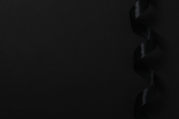 Black ribbon on black background, space for text