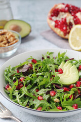 A plate with green rocket salad with pomegranate and avocado