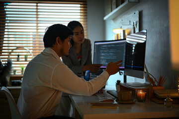 IT software developers team brainstorming and programming on desktop computer in dark room
