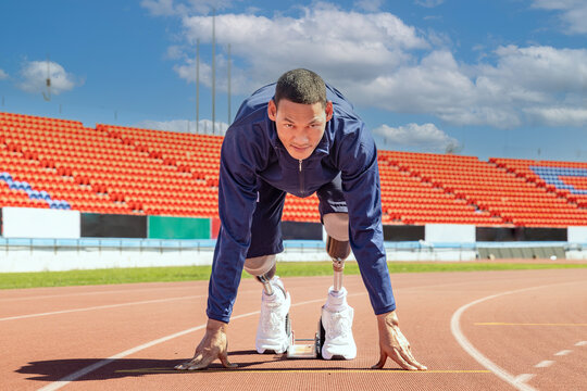 Asian para-athlete with prosthetic blades leg in stadium practicing workout for Paralympic running competition. Amputee sportsman runner practicing running workout. Disabled athlete man sport concept.