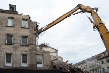 Dismantling by builders of an old building with several floors using an excavator with a...
