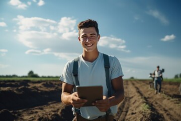 Naklejka premium photograph of Young farmer smiled happily. Using with a tablet on the plowed ground.