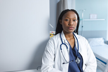 Portrait of african american female doctor wearing lab coat in hospital room, copy space