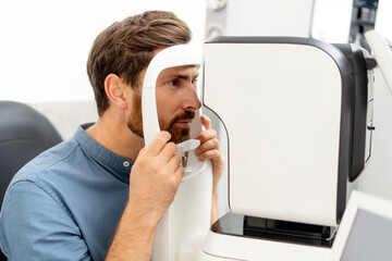Male patient making diagnostics of intraocular pressure on special ophthalmic equipment