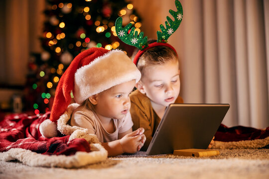 Focused children looking at tablet on christmas and new year's eve at home.