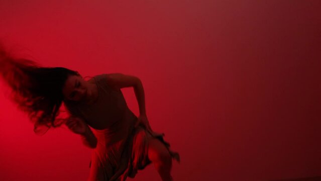 Young artistic woman expressing herself in blood red room dancing