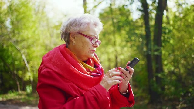 Elderly woman using smartphone outdoors