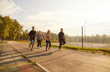 People wearing sportswear jogging along a path in the park having sport workout. Young happy...