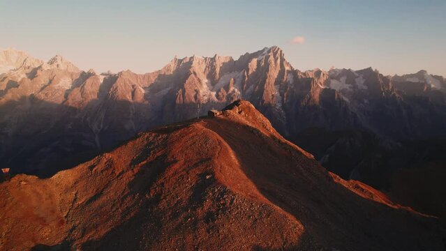 golden hour at mountain top Bivacco Pascal and testa licony. Mont Blanc massif on horizon, cinematic aerial shot