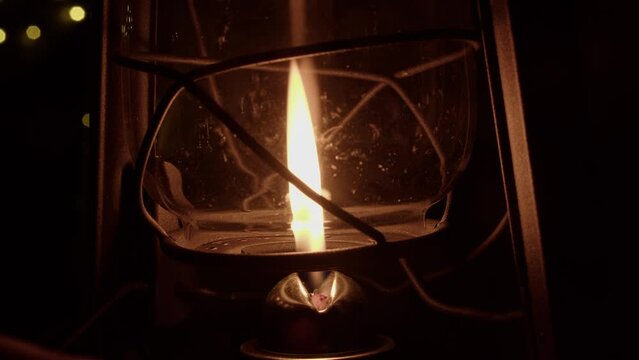Glass globe of traditional oil lamp raised, flame diminished to black