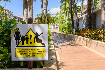 Sign at a path warning users that children must be supervised, and the path may be slippery.