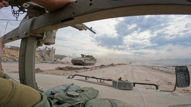 A Humvee speeding through war-torn Gaza as Namer APC heads in opposite direction