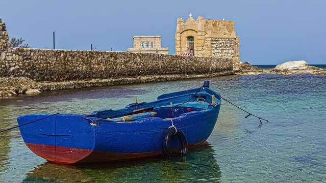 Wooden Boat With Ruins Of Torre di Ligny In The Background At Trapani, Sicily, Italy. Timelapse