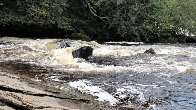 Flood and strong current with white foam of Dochart river near Killin, Scotland, United Kingdom