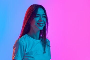 Portrait of beautiful woman in her 30s smiling, posing against gradient pink blue studio background...