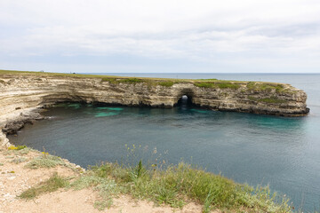 Obraz premium Cape Tarkhankut on the Crimean peninsula. The rocky coast of the Dzhangul Reserve in the Crimea. The Black Sea. Turquoise sea water. Rocks and grottoes of Cape Tarkhankut.
