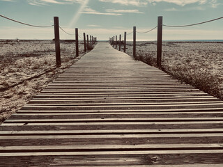 Fototapeta premium Wooden path on the beach to reach the sea.