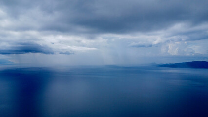 Thunderclouds and rain over the sea. Aerial view of rain over the sea on the horizon.